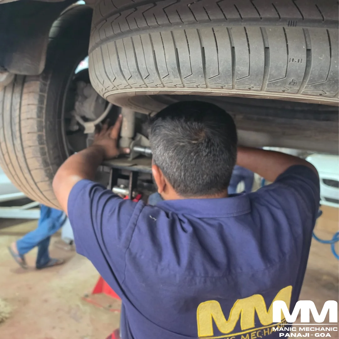 Technician working beneath a raised vehicle near the wheel assembly