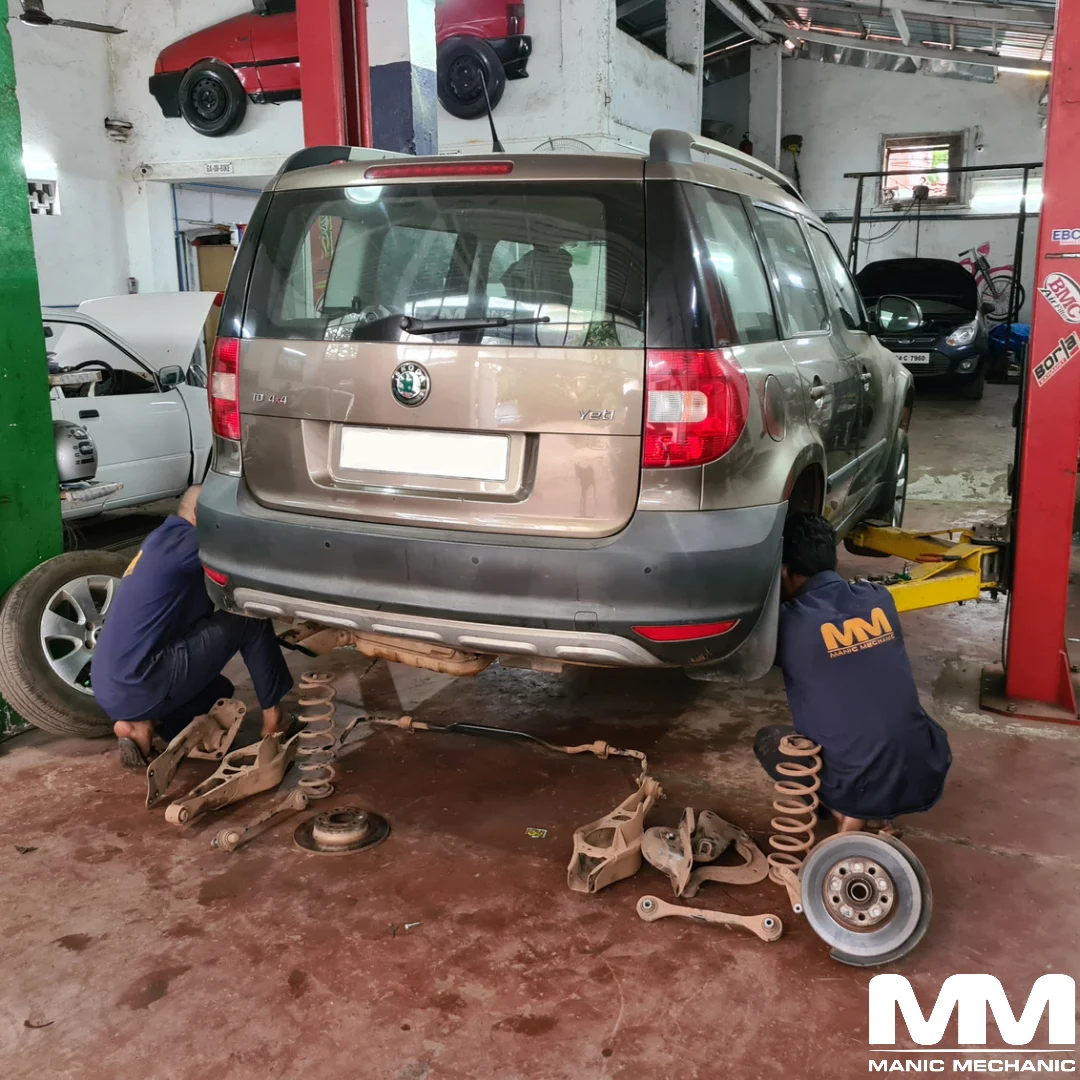 Technicians working on the rear suspension of a Skoda Yeti